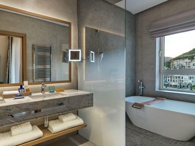 Modernes Hotelbad mit freistehender Badewanne, großem Spiegel und eingebauten LED-Leuchten.