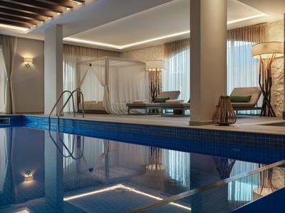 Moderner Innenpool mit Liegestühlen und indirekter Beleuchtung in einem Hotelbereich.