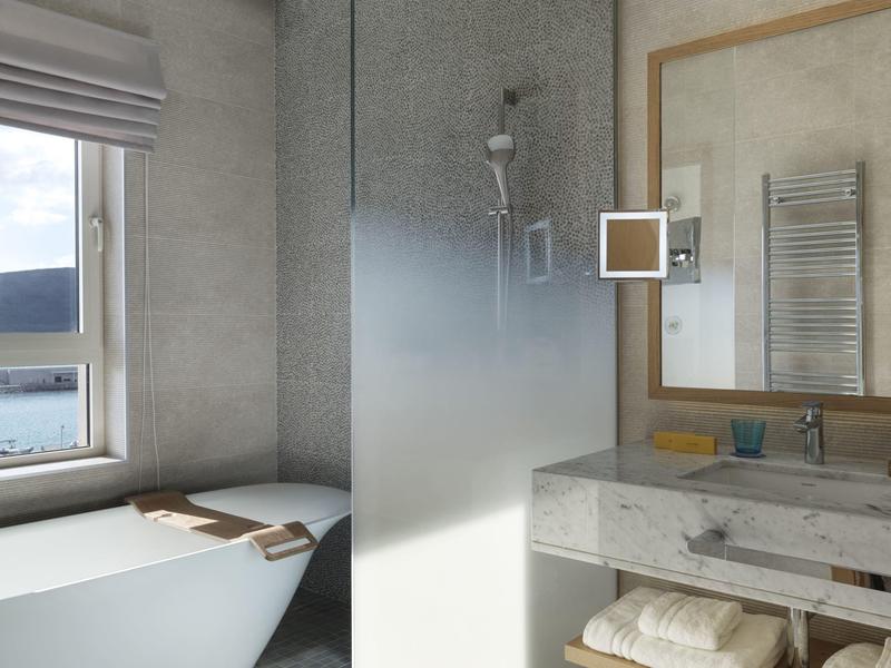 Moderne badkamer met vrijstaand ligbad, raamzicht en wastafel met handdoeken eronder.