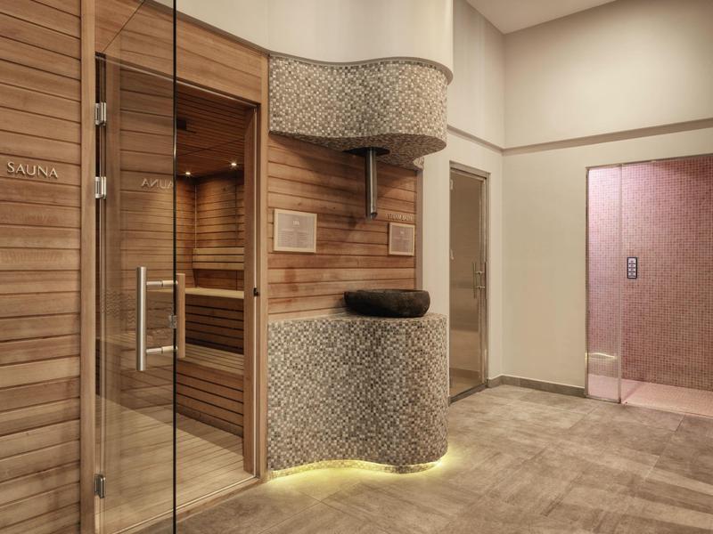 Moderne wellnessruimte met sauna, houten bekleding en zachte verlichting.