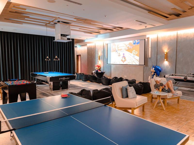 Moderne recreatieruimte met tafeltennistafel, biljarttafel en projectiescherm in een hotel.