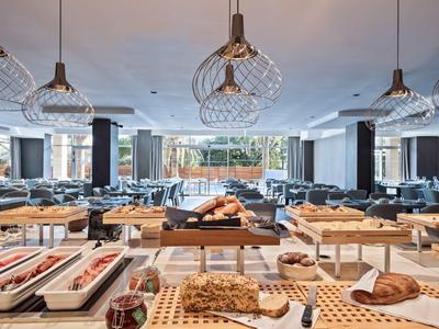 Bufet z różnymi potrawami i bułkami w nowoczesnej restauracji z dużymi oknami.