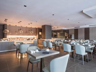 Nowoczesna restauracja hotelowa z elegancko nakrytymi stołami i wygodnymi krzesłami w neutralnych kolorach.