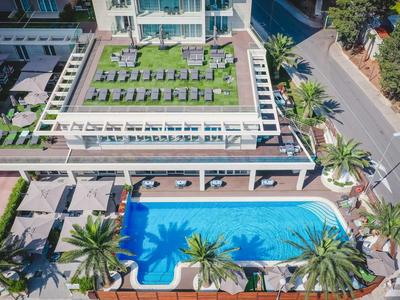 Poolanlage mit blauer Wasserfläche, Liegen und grüner Dachterrasse in modernem Wohnkomplex.