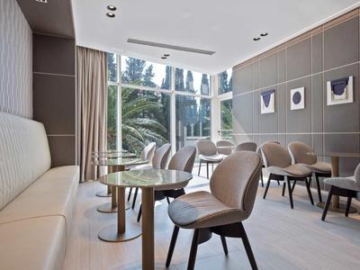 Nowoczesna, jasna przestrzeń z miejscami do siedzenia, stołami i krzesłami przy dużych oknach.