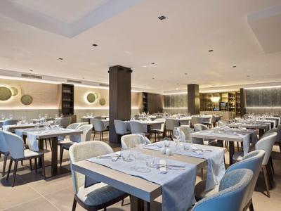 Nowoczesna restauracja z niebieskimi krzesłami i białymi obrusami w hotelu.