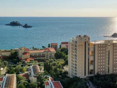Städtische Küstenlandschaft mit hohen Gebäuden, Bäumen und zwei kleinen Inseln im blauen Meer.