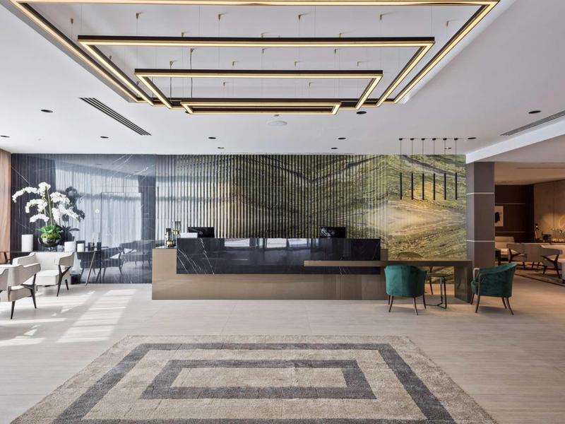 Moderner Empfangsbereich mit großem Tresen, glänzendem Boden und stilvoller Beleuchtung.