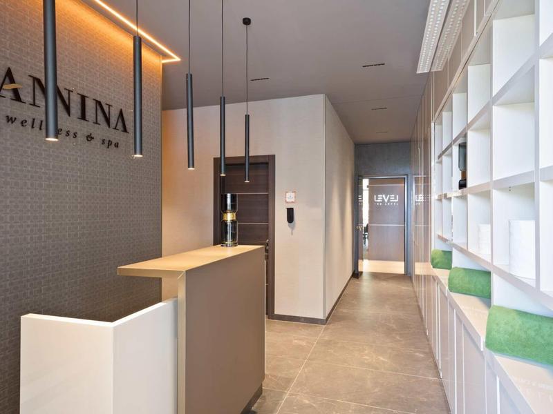 Moderner Empfangsbereich mit Theke, weißen Wänden, Regalen und grauem Bodenbelag.