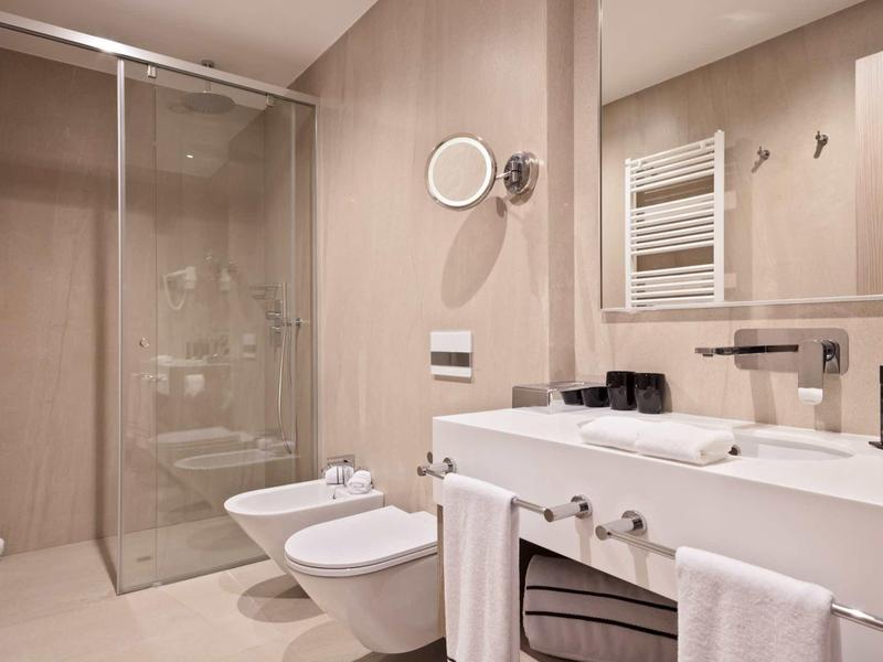 Modernes Badezimmer mit Glas-Dusche, WC, Bidet, großem Waschbecken und hellen Wandfliesen.