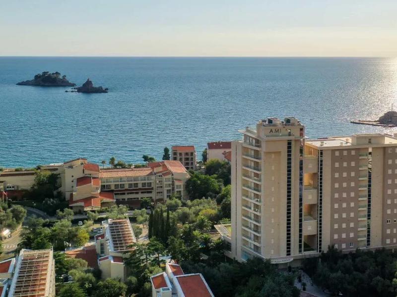 Städtische Küstenlandschaft mit hohen Gebäuden, Bäumen und zwei kleinen Inseln im blauen Meer.