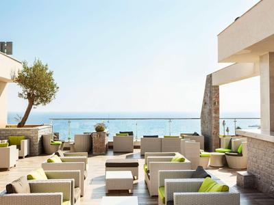 Taras z nowoczesnymi meblami i widokiem na morze pod czystym niebem.