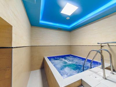 Moderner Whirlpool mit klaren Linien, blauer LED-Decke und beiger Wandverkleidung.