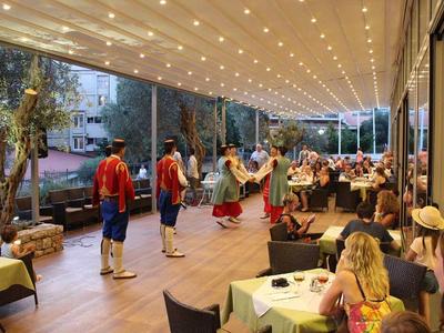 Tancerze w tradycyjnych strojach występują pod oświetlonym zadaszeniem przed publicznością na zewnątrz.