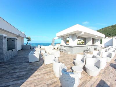 Jasny taras na dachu z białymi meblami i widokiem na morze przy czystym niebie.