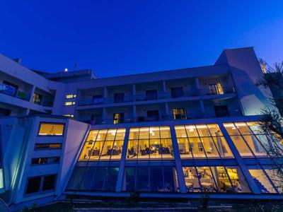 Nowoczesny budynek hotelu z oświetlonymi oknami o zmierzchu pod czystym niebem.