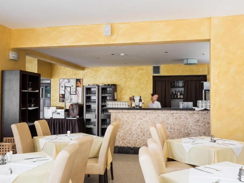 Modernes Restaurant mit beigen Stühlen, gedeckten Tischen und gelben Wänden, geschickt beleuchtet.