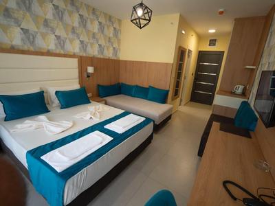 Modernes Hotelzimmer mit Doppelbett, blauen Kissen, Sitzecke, Holzdekor und Schreibtisch.