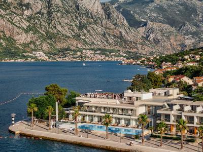 Hotel mit Pool an Küste vor bewaldeten Bergen und blauem Wasser