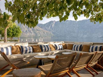Gemütliche Terrasse mit Sitzbereich, Kissen und Blick auf Berge und See