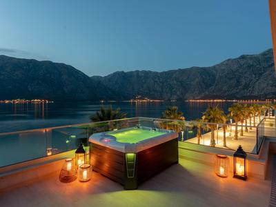 Abendliche Terrasse mit Whirlpool, Laternen und Blick auf das Meer und Berge.