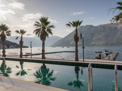 Pool mit Palmen und Blick auf die Bucht und Berge bei Sonnenuntergang