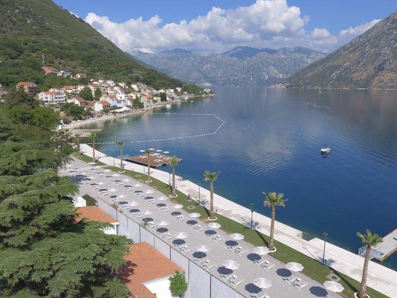 Moderní hotelový pokoj se dvěma jednolůžky, psacím stolem, TV a posezením.