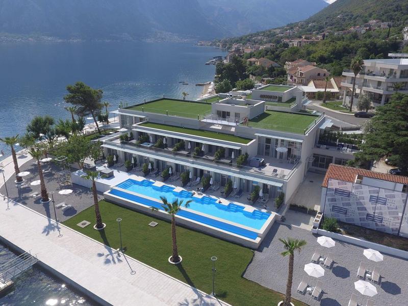 Moderní hotelový komplex s bazénem a terasou na pobřeží s výhledem na hory