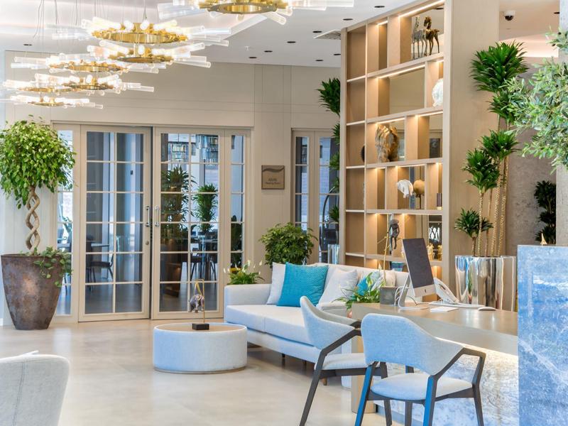 Světlé, moderní hotelové lobby s pohodlným sezením, rostlinami a dekorativním osvětlením.