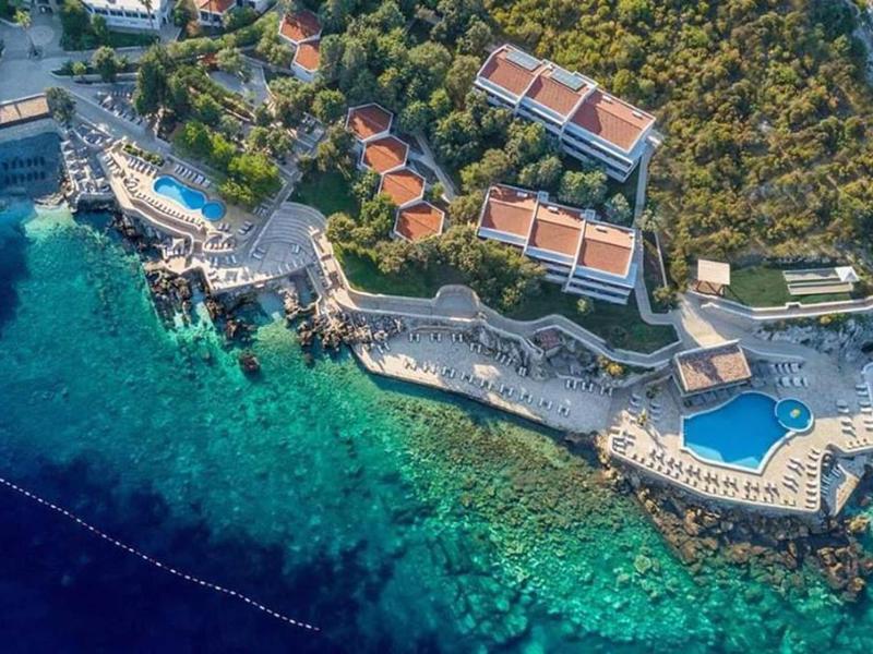 Aerial view of a resort with pools and piers on turquoise sea