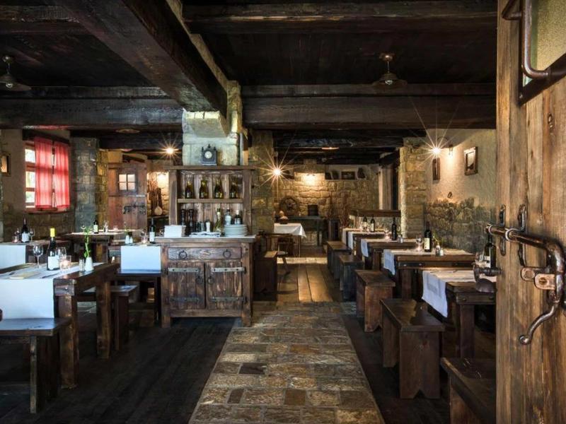 Rustic restaurant with wooden tables, benches, and dim lighting