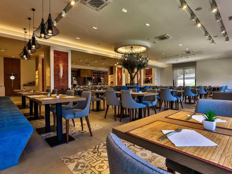 Modern restaurant with blue chairs and wooden tables in a warmly lit room.