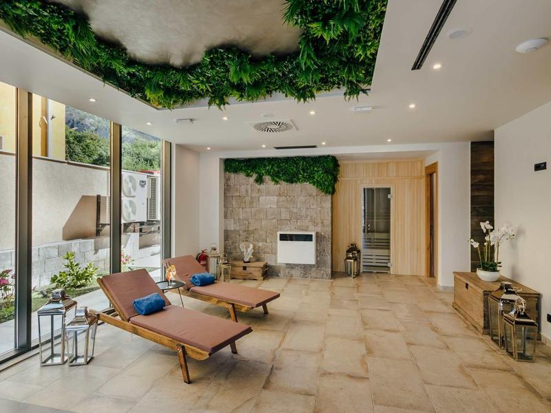 Salle de bien-être moderne avec chaises longues, plantes et cheminée dans un cadre lumineux.