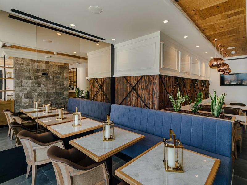 Restaurant moderne avec banquettes bleues, tables en bois et décoration contemporaine.