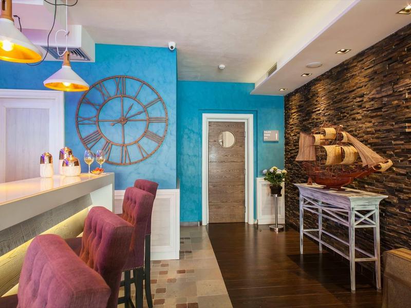 Bar de hotel con decoración moderna, sillas altas, pared azul y detalles marinos.