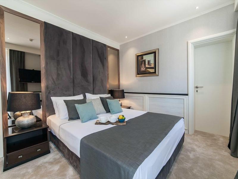 Dormitorio moderno con cama doble, cabecero acolchado, lámpara de noche y decoración sencilla.