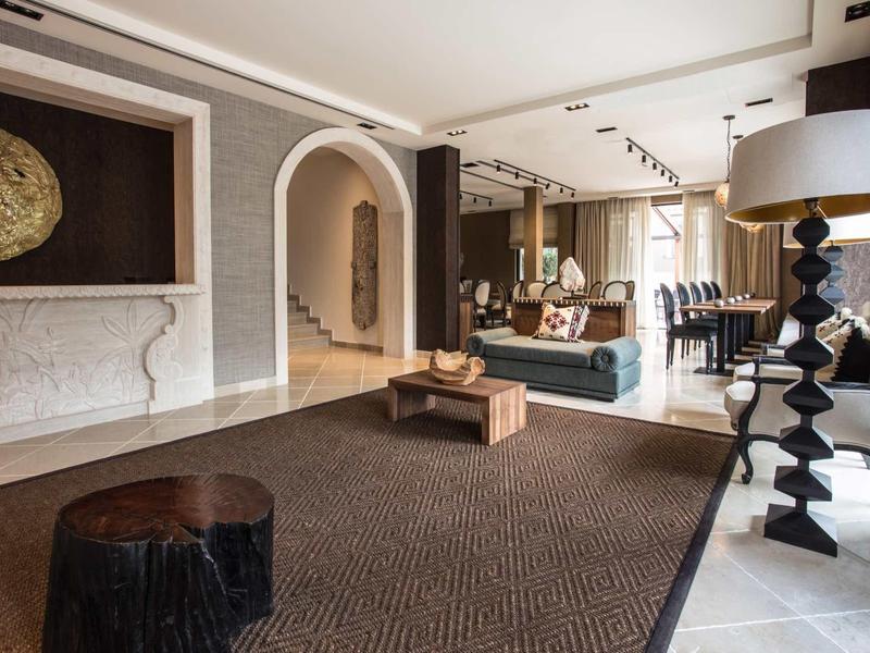 Modernes Wohnzimmer mit großen Fenstern, braunem Teppich, schwarz-weißer Dekoration und gemütlicher Atmosphäre.