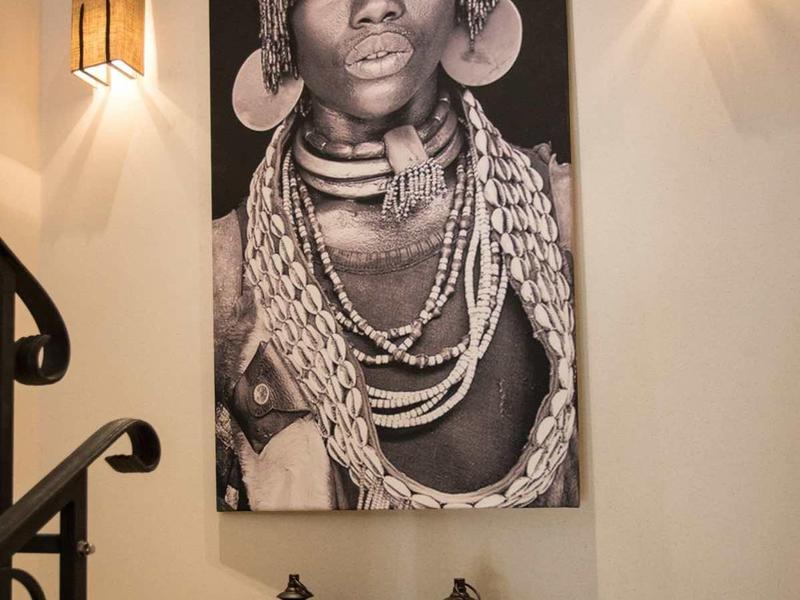 Schwarz-weiß Bild einer Frau mit Schmuck an der Wand, flankiert von zwei Wandlampen und zwei Laternen unten.