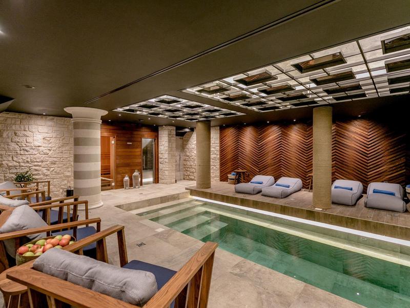 Moderner Innenpool mit Holz- und Steinverkleidung, bequemen Sesseln und indirekter Beleuchtung.