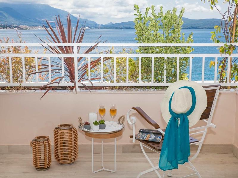 Balkon mit zwei Stühlen, Tisch, Getränken, Büchern und Meerblick im Hintergrund.