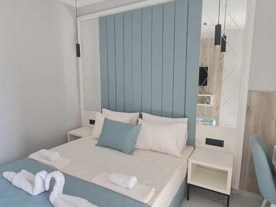 Modernes Hotelzimmer mit Doppelbett, blauer Wandverkleidung und zwei Handtuchfiguren.