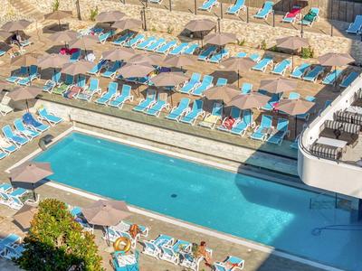 Piscina all'aperto con lettini e ombrelloni in un hotel.