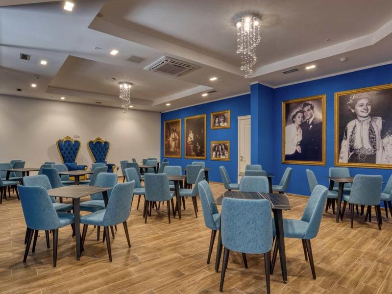 Moderner Speisesaal mit blauen Stühlen, Holzboden und Wandbildern in goldenem Rahmen.