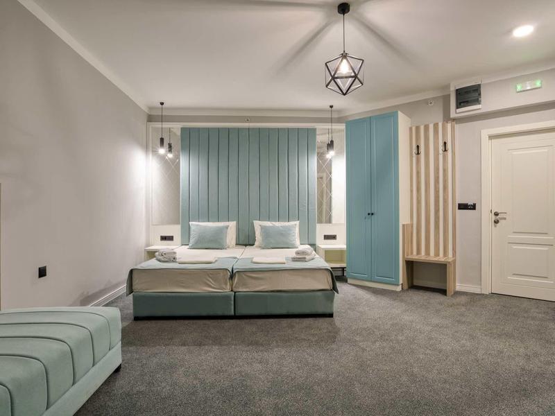 Modernes Hotelzimmer mit Doppelbett, blauen Akzenten und grauem Teppichboden