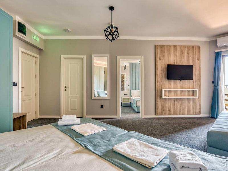 Modernes Hotelzimmer mit Doppelbett, Fernseher an der Wand und Balkon mit Meerblick.