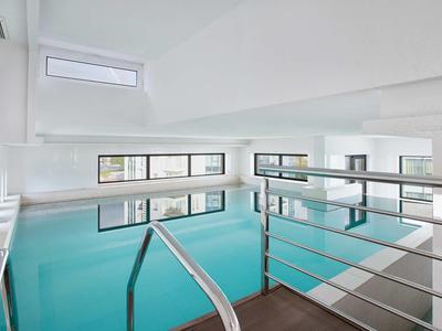 Moderní, světlý vnitřní bazén s kovovým zábradlím a velkými okny