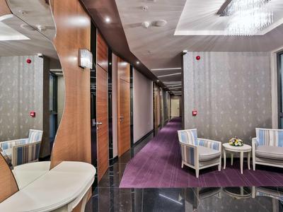 Moderní hotelová chodba s dřevěnými dveřmi, zrcadly a posezením s křesly a stolkem