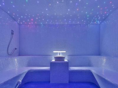 Hellblaue Dampfbadkabine mit Mosaikfliesen und Sternenhimmelbeleuchtung an Decke und Wänden.