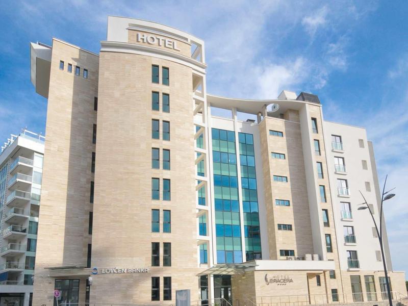 Modernes mehrstöckiges Gebäude mit Glasfassade und beigem Putz unter blauem Himmel.