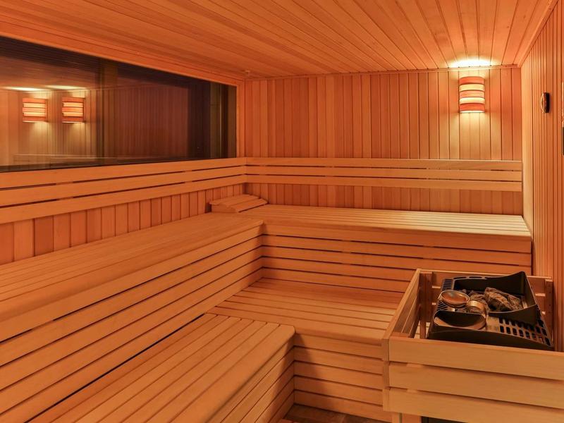 Innensauna mit mehrstufigen Holzbänken, Holzverkleidung und elektrischem Saunaofen.